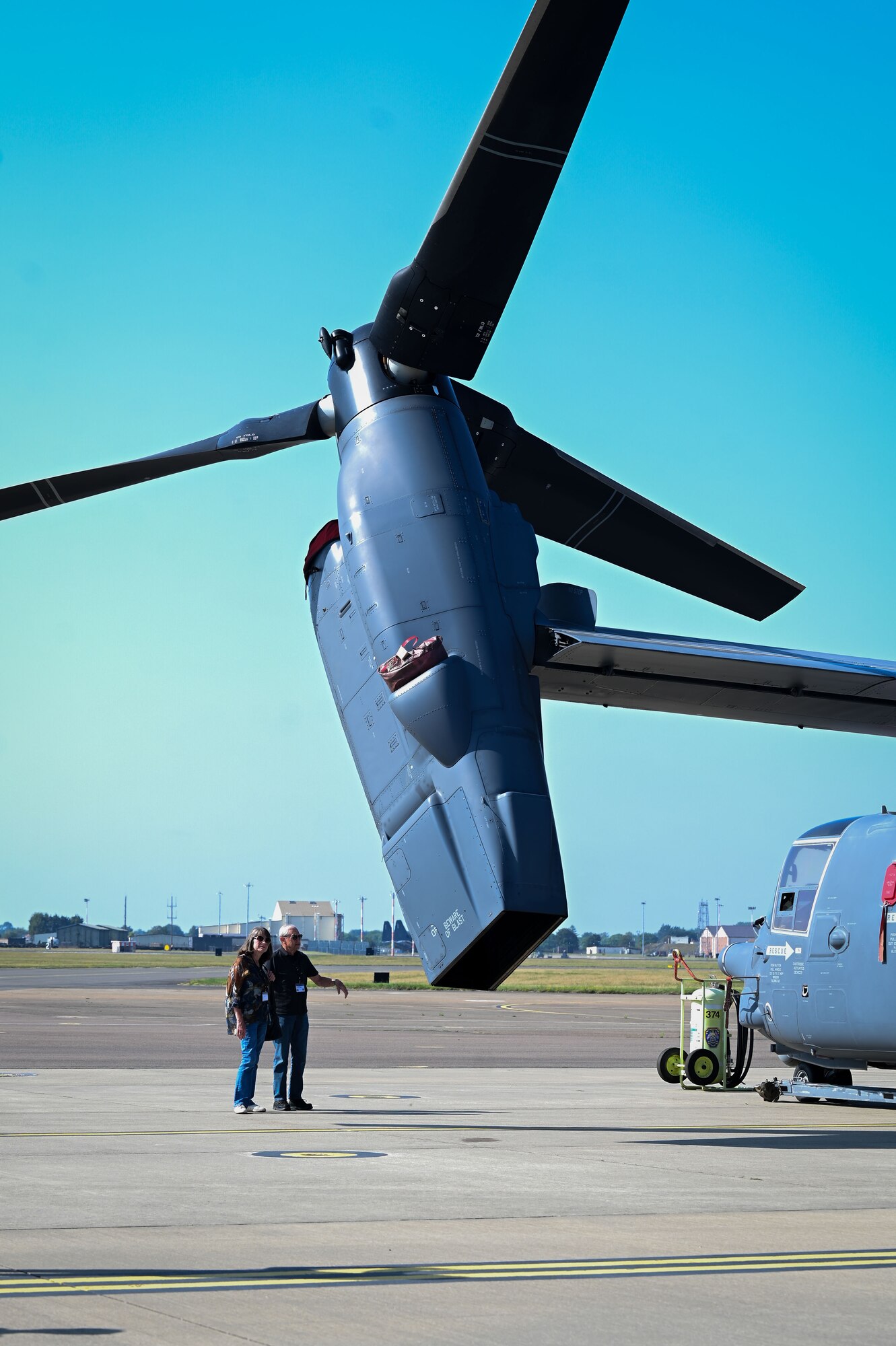 Two retired servicemembers stand in front of a CV-22 Osprey assigned to the 352nd Special Operations Wing on the flightline during the 2025 Retiree Appreciation Day at RAF Mildenhall, England, Aug. 15, 2025.