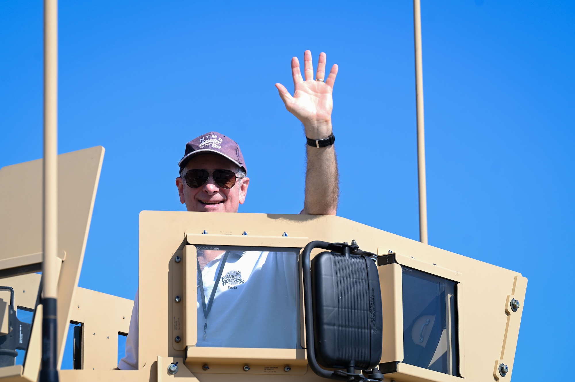 A retired servicemember waves from atop a Joint Light Tactical Vehicle during the 2025 Retiree Appreciation Day at RAF Mildenhall, England, Aug. 15, 2025.
