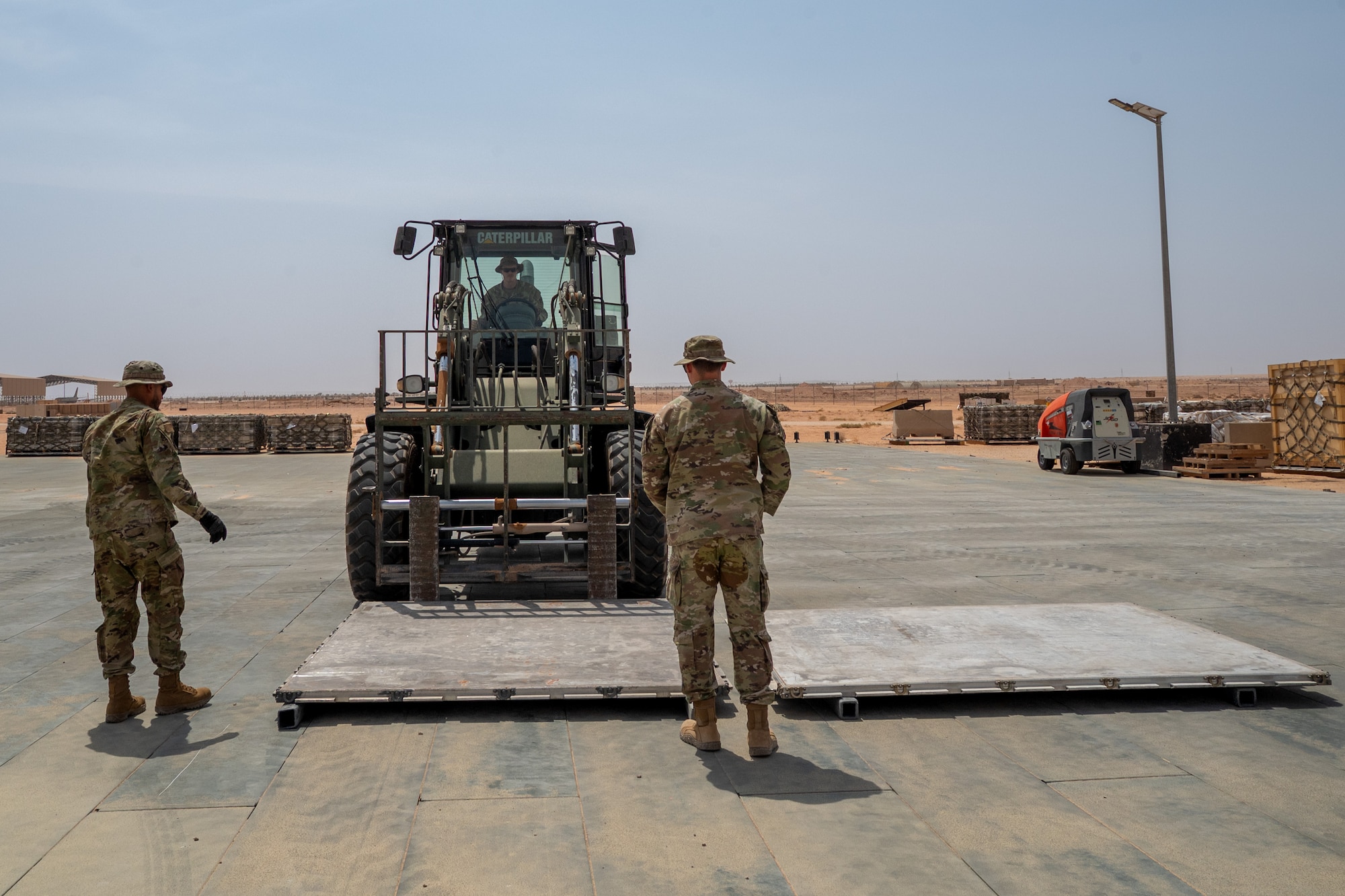 Airmen stand in front of forklift
