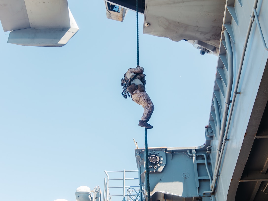 A U.S. Marine with Maritime Special Purpose Force, 22nd Marine Expeditionary Unit (Special Operations Capable), slides down a fast rope while conducting fast rope drills out of an MV-22 Osprey aboard the Wasp-class amphibious assault ship USS Iwo Jima (LHD 7), while in port at Naval Station Norfolk, Virginia, Aug. 22, 2025. Marines with the 22nd MEU(SOC) conducted fast rope drills to enhance readiness in support of their regularly scheduled deployment. (U.S. Marine Corps photo by Sgt. Tanner Bernat)