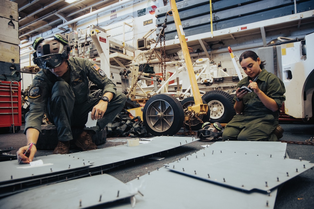 U.S. Marine Corps Cpl. Colby Conklin, left, a crew chief, and Lance Cpl. Christine Bedolla, a tiltrotor mechanic, both with Marine Medium Tiltrotor Squadron 263 (Reinforced), 22nd Marine Expeditionary Unit (Special Operations Capable), label panels while conducting maintenance on a MV-22 Osprey aboard the Wasp-class amphibious assault ship USS Iwo Jima (LHD 7), while underway in the Atlantic Ocean, Aug. 18, 2025. The 22nd MEU (SOC) conducted routine aircraft maintenance to enhance readiness in support of their regularly scheduled deployment. (U.S. Marine Corps photo by Sgt. Tanner Bernat)