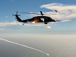 U.S. Air Force HH-60G Pave Hawk helicopter assigned to the 129th Rescue Squadron, California Air National Guard deploys countermeasure flares as a U.S. Air Force F-15D Eagle from the 144th Fighter Wing, California Air National Guard, maneuvers overhead during a joint over-water test flight, Aug. 20, 2025.