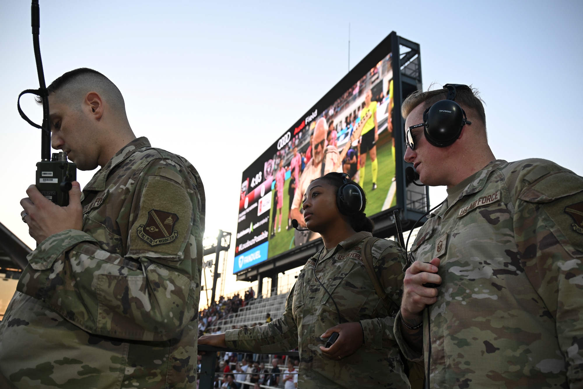 From left, U.S. Air Force Staff Sgt. Anthony Bailey, Tech. Sgt. Tashana Fustino, and Master Sgt. Sean Moffit, all assigned to the 1st Helicopter Squadron, communicate with UH-1N helicopter pilots in preparation for a flyover at Audi Field, Washington, D.C., Aug. 23, 2025. The three-aircraft flyover took place ahead of the D.C. United vs. Inter Miami soccer game.
