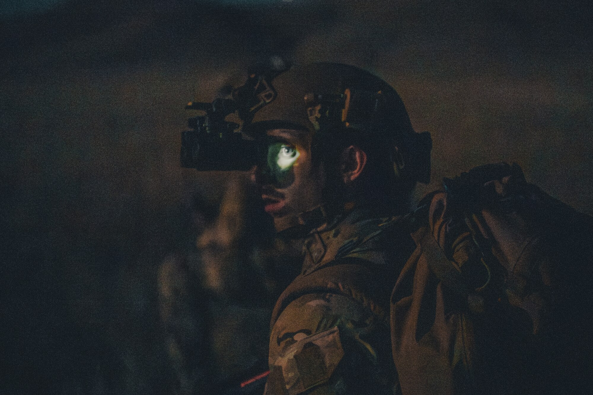 An Airman wearing night vision goggles looks into distance.