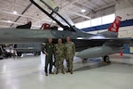 From left, U.S. Air Force Maj. Gen. Gregory Kreuder, commander, 19th Air Force, Tech. Sgt. Andrew Quiroz, 162nd Aircraft Maintenance Squadron avionics technician, and Chief Master Sgt. Keith Scott, command chief 19th Air Force, gather for a photo  at Morris Air National Guard Base, Ariz., Aug. 19, 2025. Quiroz was recognized for his contributions to the maintenance of Aircraft 379. Aircraft 379, critical for student pilot training, underwent depot-level maintenance, averting a year long wait and saving millions of dollars. This initiative exemplifies the 162nd Wing’s commitment to efficient resource management in support of the 19th Air Force mission to produce the next generation of aviators. (U.S. Air National Guard photo by Staff Sgt. Guadalupe Beltran)