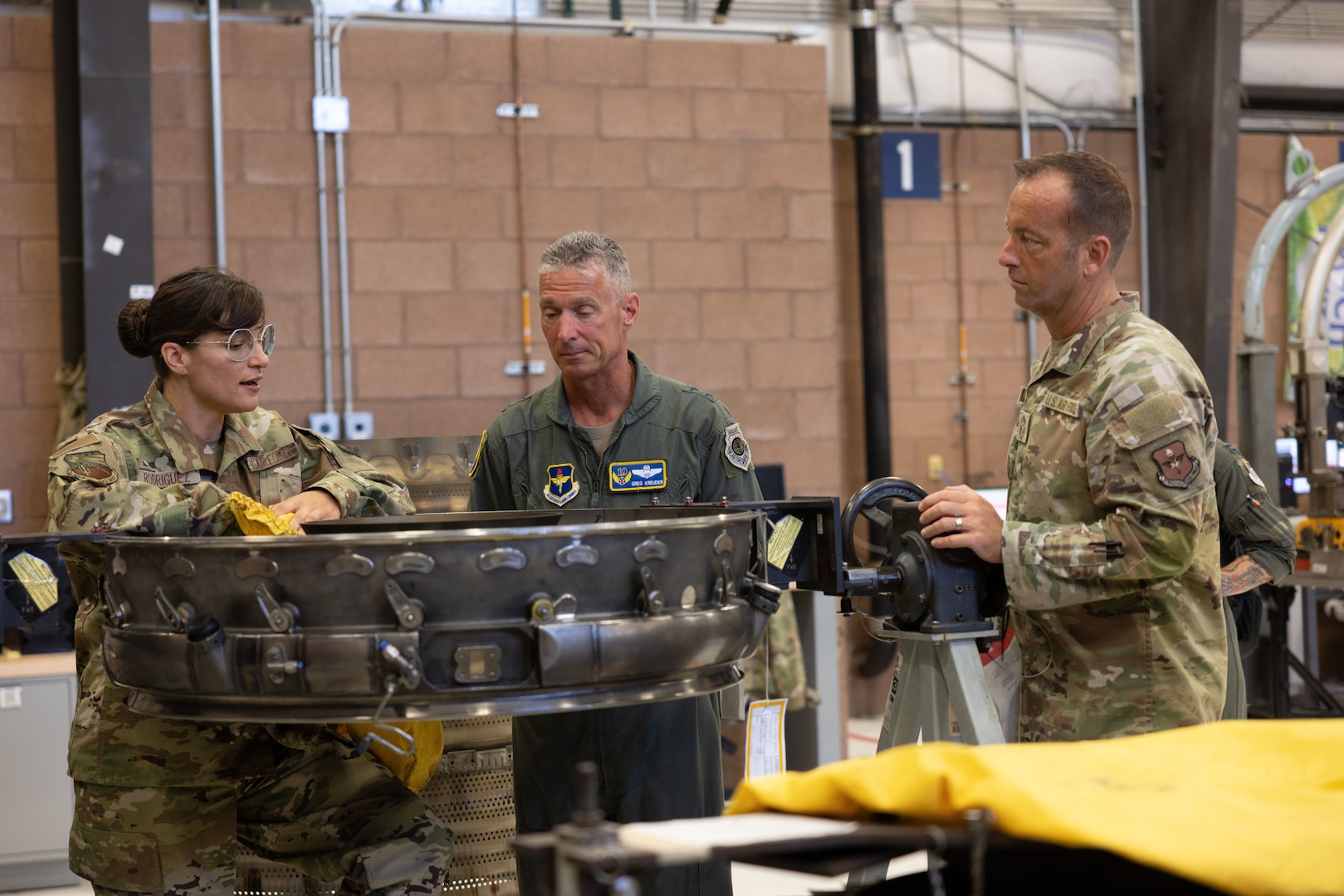 From left, U.S. Air National Guard Master Sgt. Stacey Rodriguez, 162nd Jet Engine Intermediate Maintenance supervisor, U.S. Air Force Maj. Gen. Gregory Kreuder, commander 19th Air Force, and Chief Master Sgt. Keith Scott, command chief 19th Air Force, discuss aircraft engine maintenance at the Jet Engine Intermediate Maintenance section at Morris Air National Guard Base, Ariz., Aug. 19, 2025. While most units only have one engine type, the 162nd JEIM has a dual configuration that supports simultaneous maintenance on both General Electric and Pratt & Whitney engines. By sustaining two fully equipped support sections, the wing maintains unmatched flexibility to support multiple F-16 blocks and diverse mission requirements. (U.S. Air National Guard photo by Staff Sgt. Guadalupe Beltran)