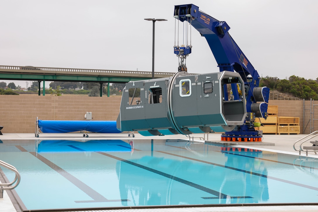 A helicopter dunker module, braced by a jib crane, sits above an underwater egress training tank at the 21 Area Combat Water Survival Training Facility at Marine Corps Base Camp Pendleton, California, Aug. 13, 2025. The newly constructed facility will be capable of hosting training events such as Marine Corps swim qualification, Underwater Egress Training, and Submerged Vehicle Egress Training to ensure readiness and maintain amphibious capabilities. (U.S. Marine Corps photo by Cpl. Jacqueline Akamelu)