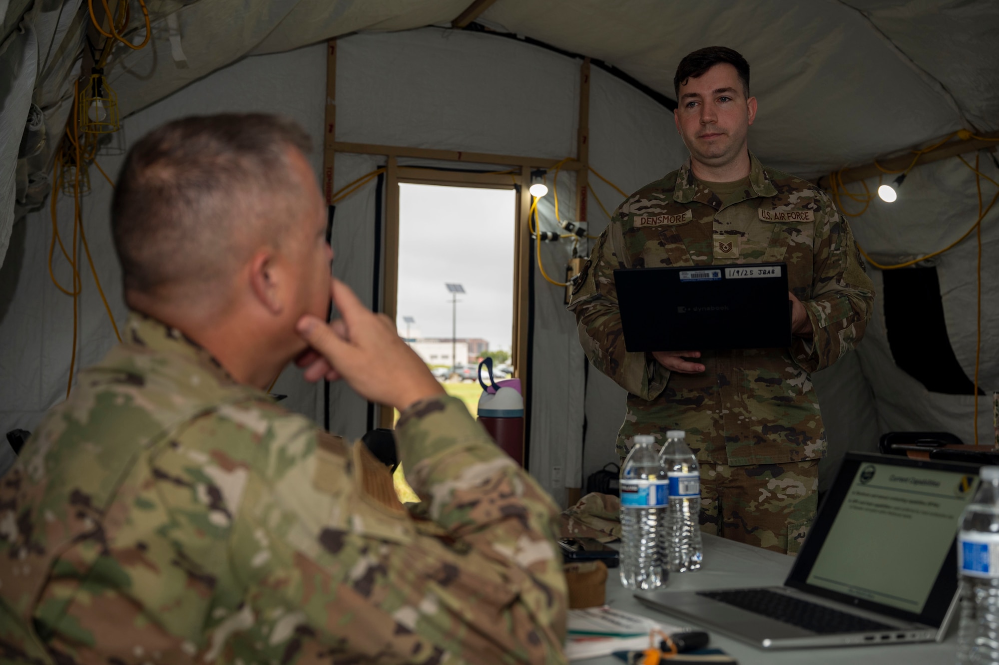 U.S. Air Force Tech. Sgt. Kristopher Densmore, an 11th Contracting Squadron contracting specialist, briefs Col. James M. Clark, commander of Joint Base Anacostia Bolling and the 11th Wing, at JBAB, Washington, D.C., Aug. 19, 2025. The squadron executed annual requirements in a three-day exercise that covered approximately 40 potential scenarios. (U.S. Air Force photo by Staff Sgt. Jordan Powell)