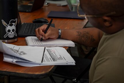 U.S. Air Force Staff Sgt. Jeffrey Bowens, an 11th Contracting Squadron contracting specialist, takes notes during a three-day exercise at Joint Base Anacostia-Bolling, Washington, D.C., Aug. 19. 2025. Scenarios included writing contracts for various construction projects, coordination with multiple military offices and navigation of both political and tactical threats. (U.S. Air Force photo by Staff Sgt. Jordan Powell)