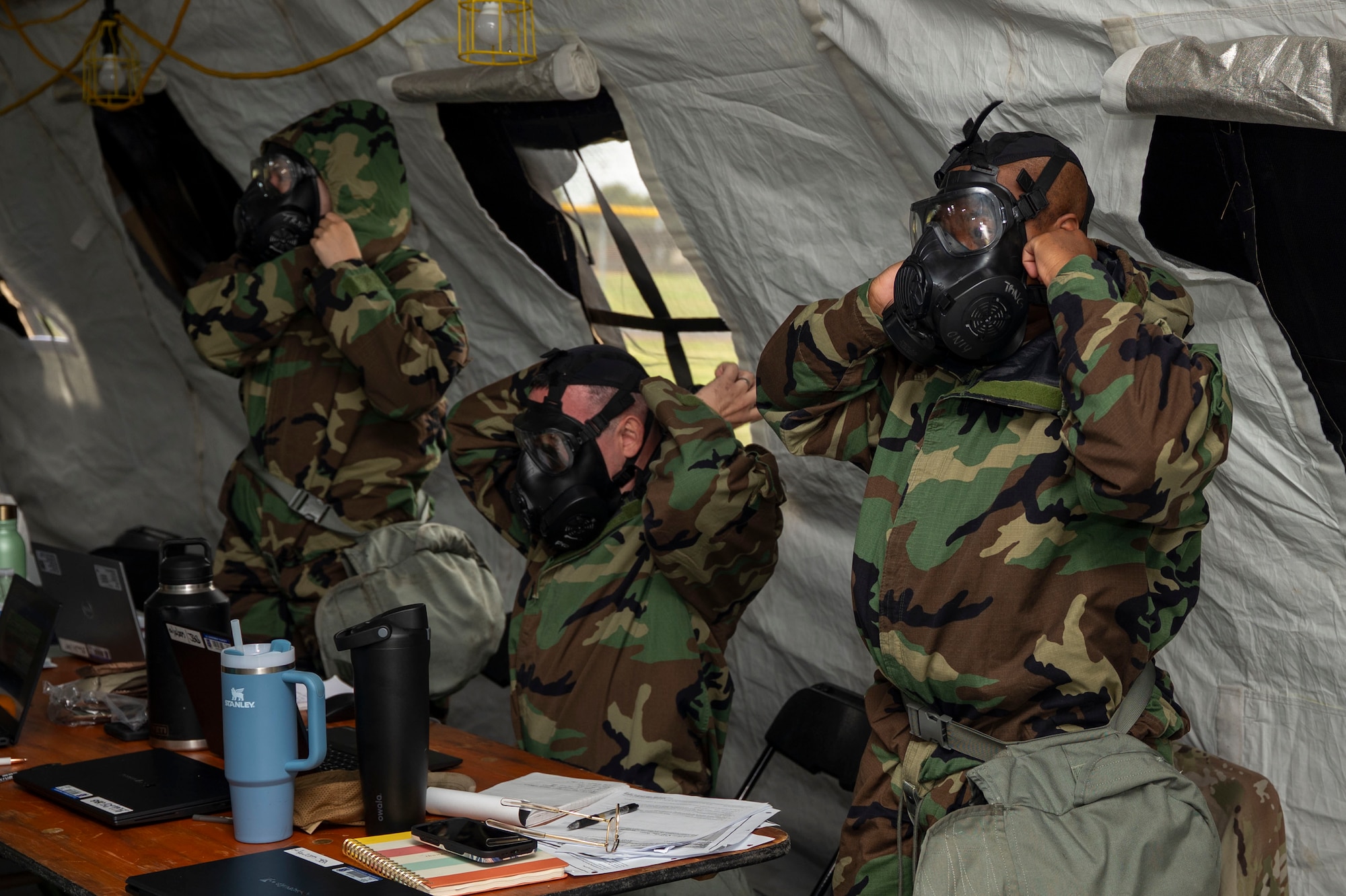 U.S. Air Force Airmen with the 11th Contracting Squadron don protective masks and Mission Oriented Protective Posture gear during an exercise at Joint Base Anacostia-Bolling, Washington, D.C., Aug. 19. 2025. The 11th CONS ensured preparedness through approximately 40 exercise scenarios, including a simulated chemical, biological, radiological, and nuclear attack. (U.S. Air Force photo by Staff Sgt. Jordan Powell)
