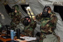 U.S. Air Force Airmen with the 11th Contracting Squadron don protective masks and Mission Oriented Protective Posture gear during an exercise at Joint Base Anacostia-Bolling, Washington, D.C., Aug. 19. 2025. The 11th CONS ensured preparedness through approximately 40 exercise scenarios, including a simulated chemical, biological, radiological, and nuclear attack. (U.S. Air Force photo by Staff Sgt. Jordan Powell)
