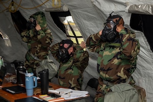 U.S. Air Force Airmen with the 11th Contracting Squadron don protective masks and Mission Oriented Protective Posture gear during an exercise at Joint Base Anacostia-Bolling, Washington, D.C., Aug. 19. 2025. The 11th CONS ensured preparedness through approximately 40 exercise scenarios, including a simulated chemical, biological, radiological, and nuclear attack. (U.S. Air Force photo by Staff Sgt. Jordan Powell)
