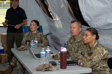U.S. Air Force Col. James M. Clark, commander of Joint Base Anacostia-Bolling and the 11th Wing, middle, Col. Angelique Nelson, 11th Mission Support Group commander, right, and Lt. Col. Rebecca Ban, 11th Contracting Squadron commander, left, receive 11th CONS exercise briefings at JBAB, Washington, D.C. Aug. 19, 2025. Two teams of ten Airmen simulated a deployed environment for three days, processed approximately 40 scenarios and briefed installation senior leadership. (U.S. Air Force photo by Staff Sgt. Jordan Powell)