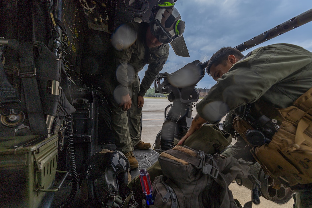 U.S. Marine Corps Cpl. Anthony Sanchez, left, and Sgt. Angel Hernandez, right, crew chiefs with Marine Light Attack Helicopter Squadron (HMLA) 775, Marine Aircraft Group 41, 4th Marine Aircraft Wing, prep their gear prior to conducting a simulated visit, board, search and seizure operation for Training Exercise Northern Strike at Camp Grayling, Michigan, Aug. 7, 2025. Northern Strike is designed to validate readiness of a Joint Reserve force to cover unique Marine Corps Reserve capabilities and support to active components on a large scale. (U.S. Marine Corps photo by Cpl. Aaron TorresLemus)