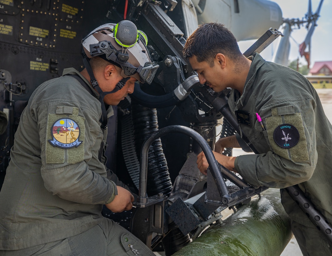 U.S. Marine Corps Cpl. Anthony Sanchez, left and Sgt. Angel Hernandez, right, crew chiefs with Marine Light Attack Helicopter Squadron (HMLA) 775, Marine Aircraft Group 41, 4th Marine Aircraft Wing, lock an M3M Gun Aircraft Unit-21 .50-caliber weapon system in position on a Utility Helicopter-1Y in preparation to conduct a simulated visit, board, search and seizure operation for Training Exercise Northern Strike at Camp Grayling, Michigan, Aug. 7, 2025. Northern Strike is designed to validate readiness of a Joint Reserve force to cover unique Marine Corps Reserve capabilities and support to active components on a large scale. (U.S. Marine Corps photo by Cpl. Aaron TorresLemus)