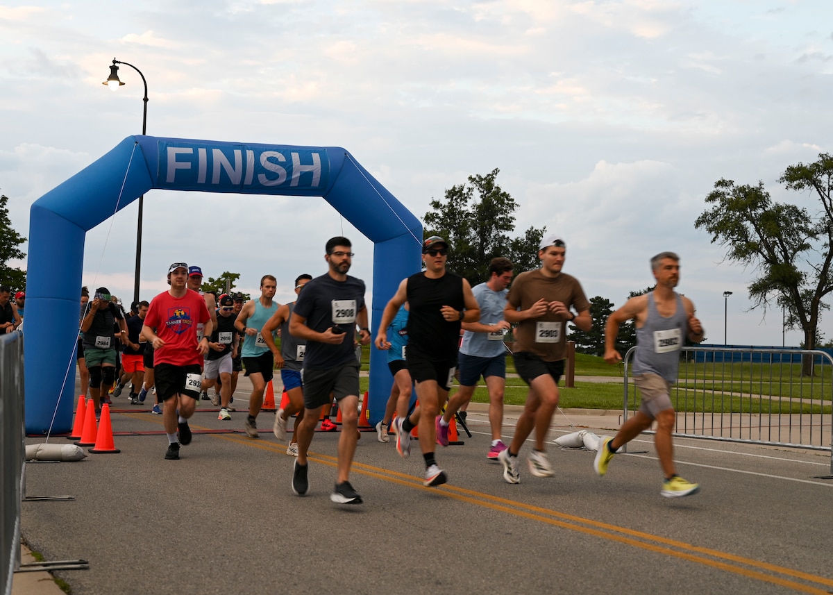 A group of people run away from a large arch that says "finish"