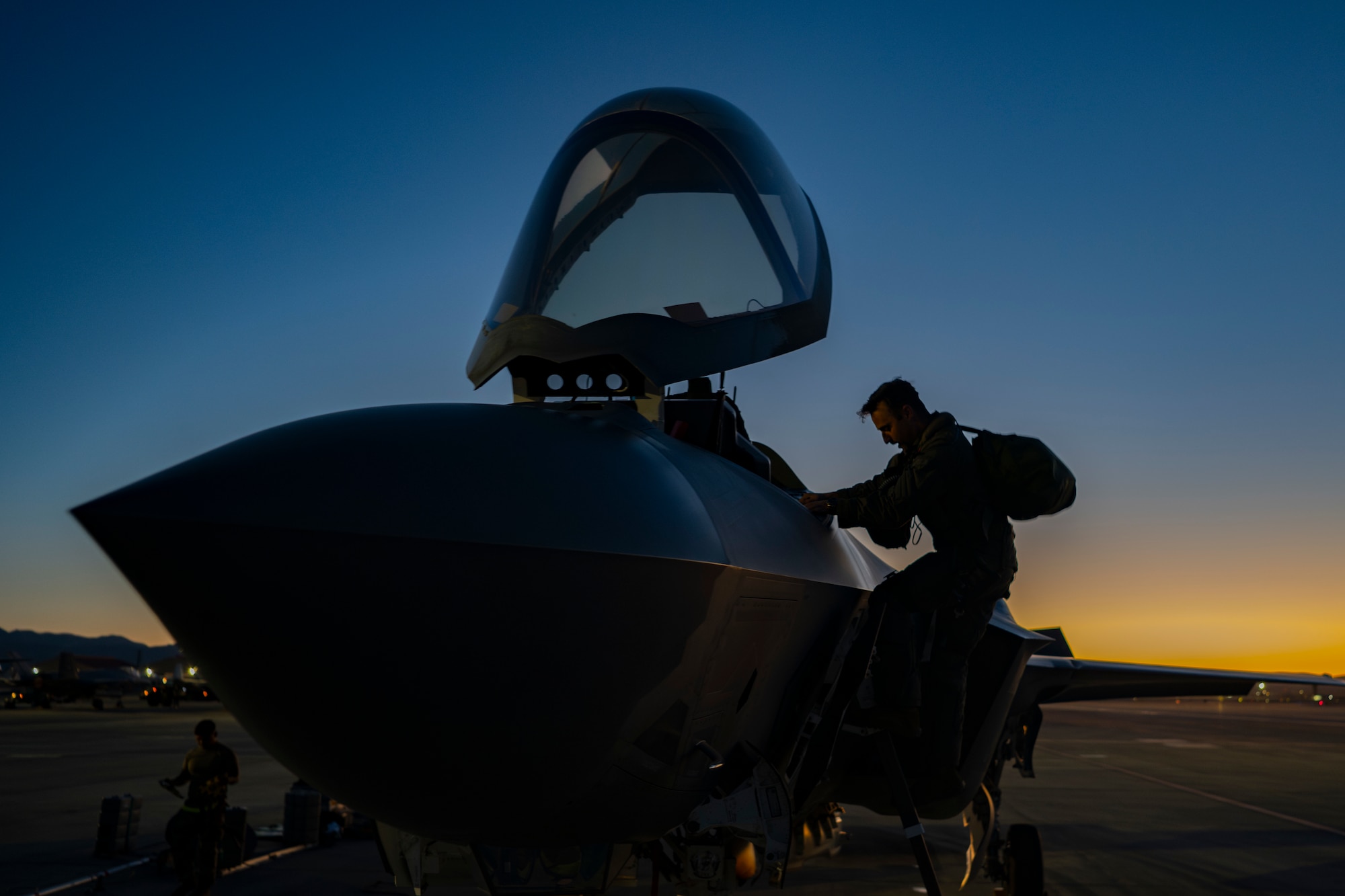 A photo of a pilot climbing down from an F-35 at dusk