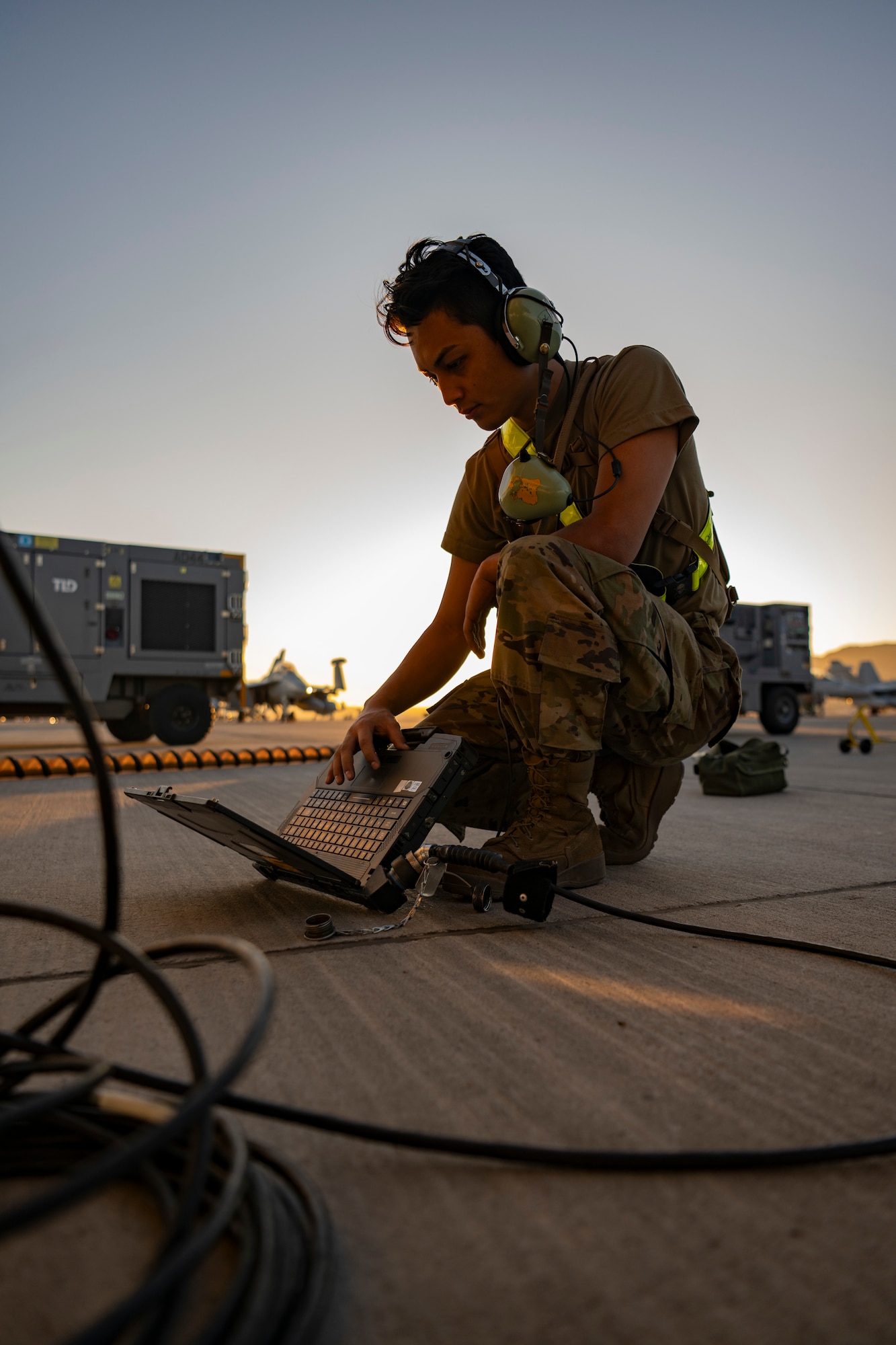 A photo of an airman on the flightline bending over a computuer
