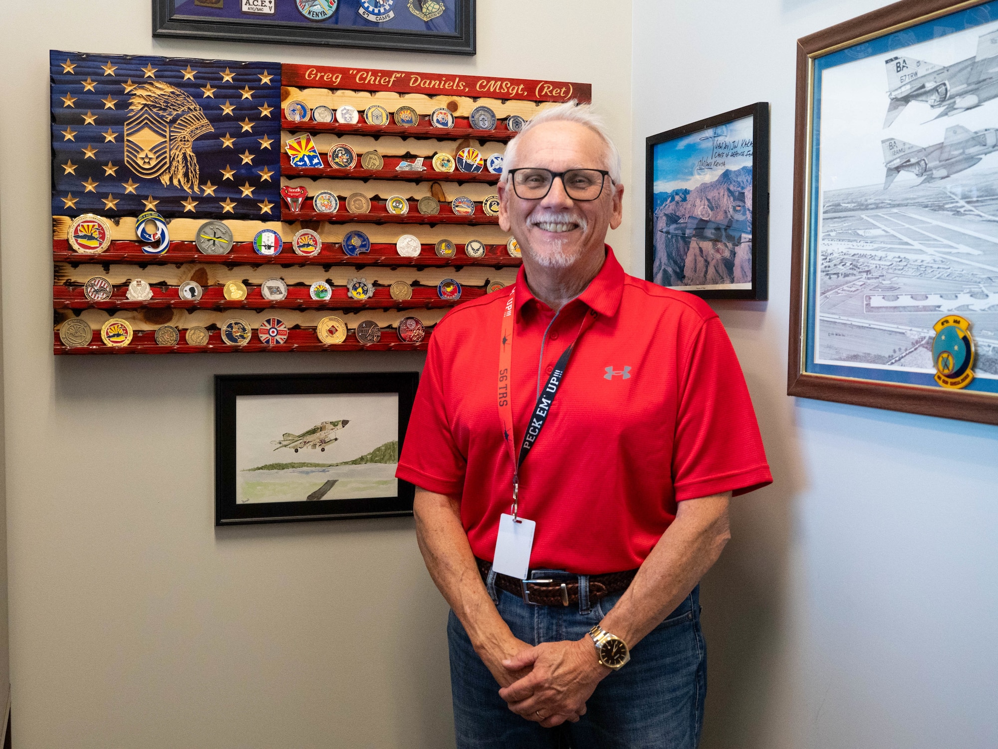 Gregory Daniels, 56th Training Squadron instructional systems specialist, stands in front of a coin display, Aug. 8, 2025, at Luke Air Force Base, Arizona.