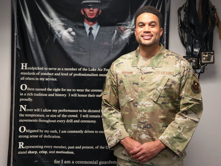 U.S. Air Force Tech. Sgt. Jacakori Burbank, Luke Honor Guard program manager, stands in front of a poster, Aug. 14, 2025, at Luke Air Force Base, Arizona.