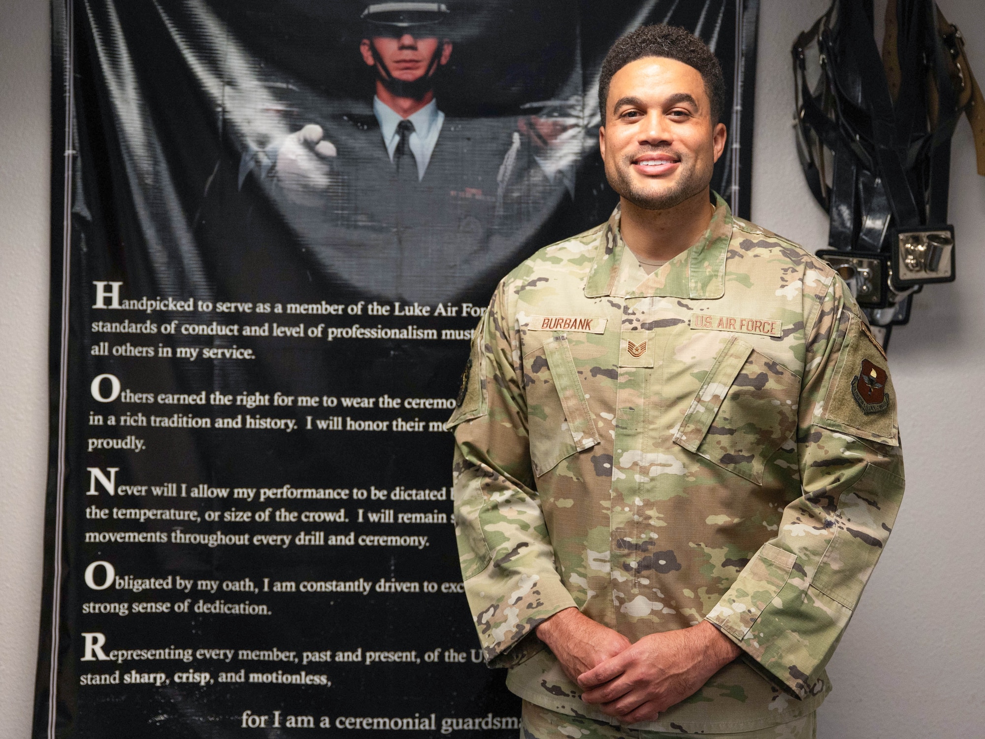 U.S. Air Force Tech. Sgt. Jacakori Burbank, Luke Honor Guard program manager, stands in front of a poster, Aug. 14, 2025, at Luke Air Force Base, Arizona.