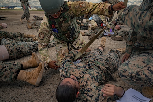 U.S. Air Force Staff Sgt. Tatiana Wilmore, 18th Aeromedical Evacuation Squadron aeromedical evacuation technician, uses an operational camouflage pattern belt as a tourniquet to treat a simulated patient during a mass casualty training event in the Indo-Pacific region, July 22, 2025. Participants faced unpredictable scenarios using live role players and limited supplies to simulate real-world constraints