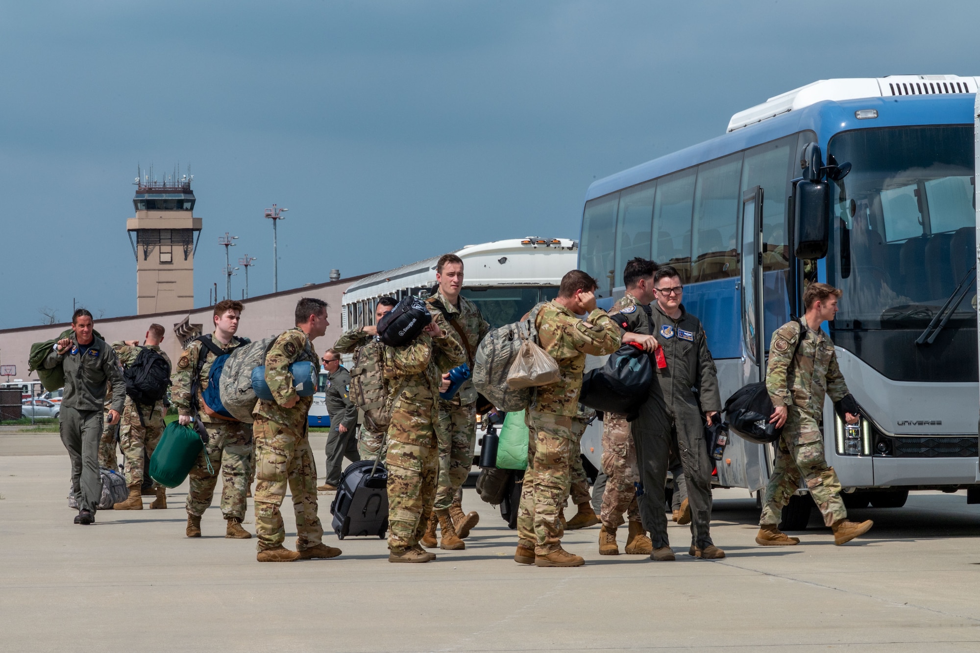 People walk on the flightline with planes parked.