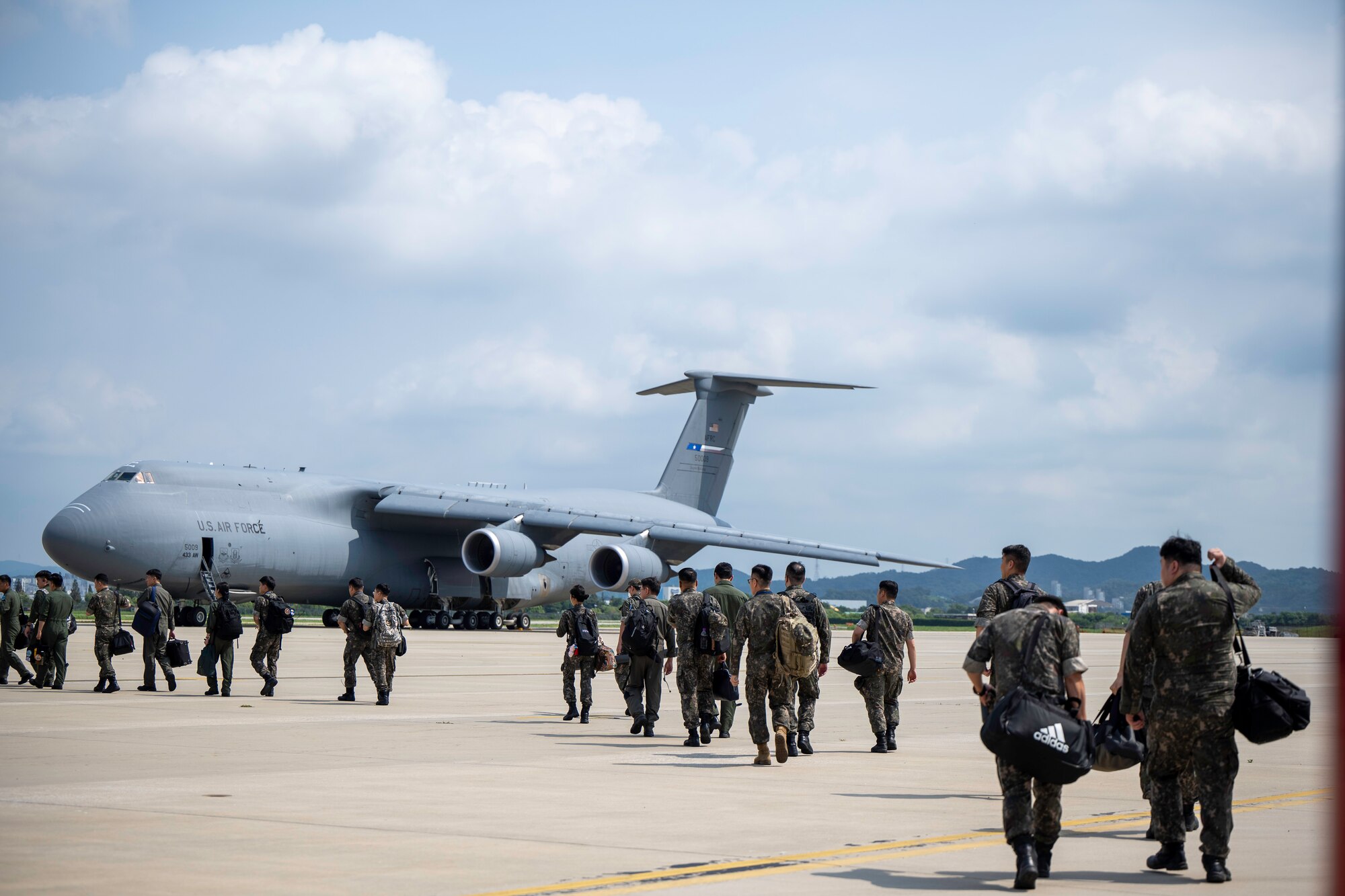 People walk on the flightline with planes parked.