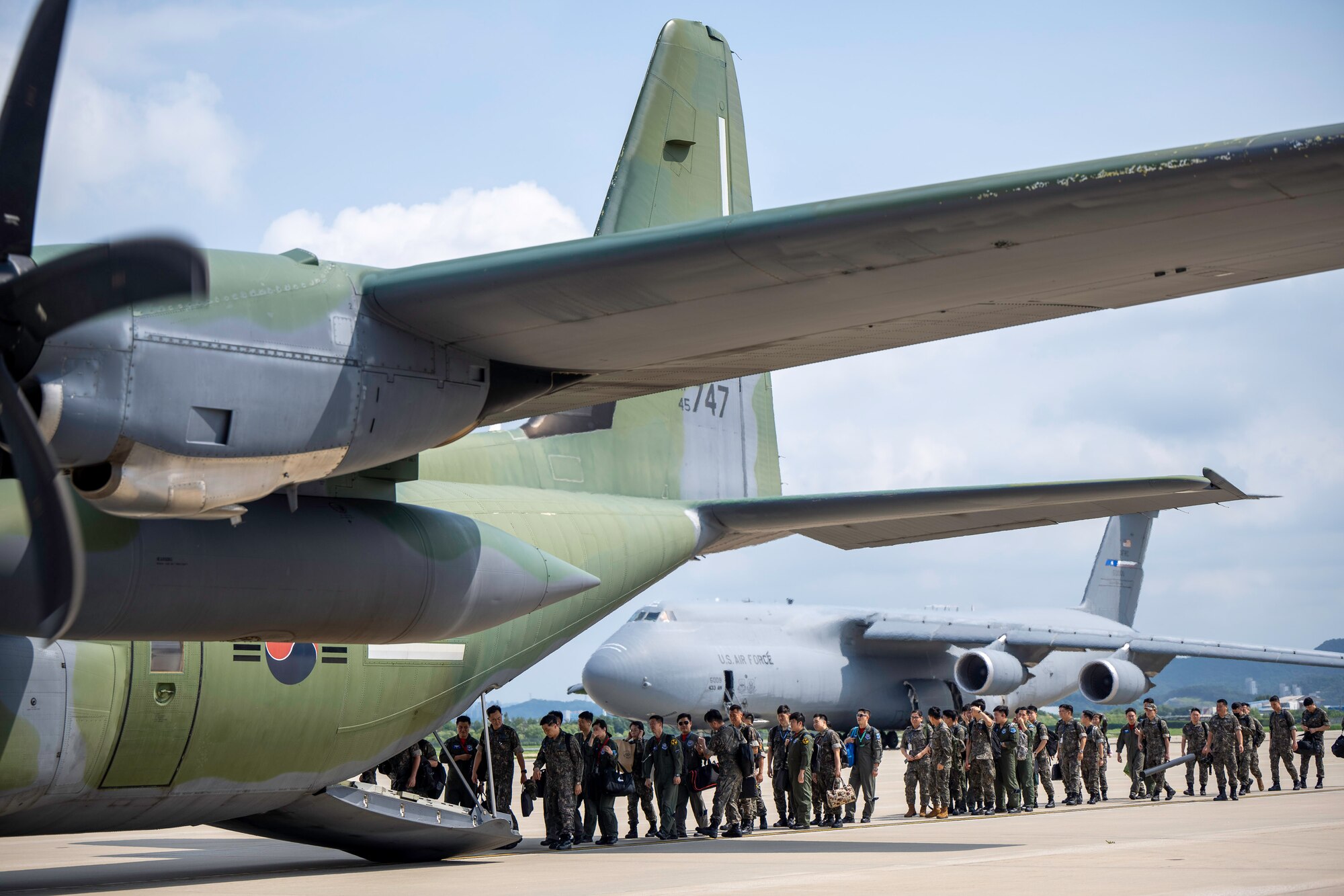 People walk on the flightline with planes parked.