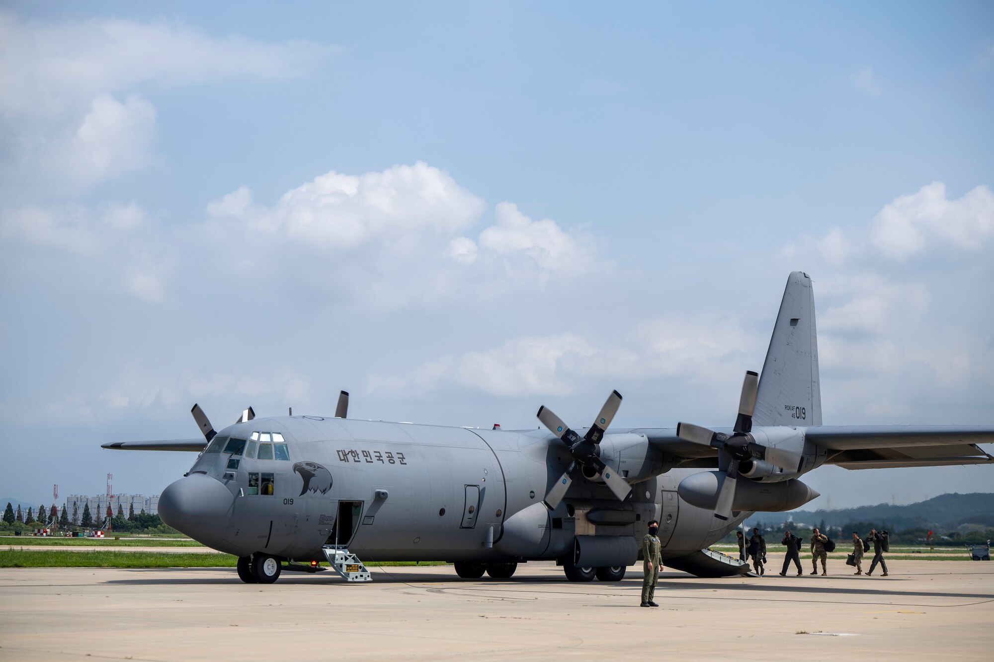 People walk on the flightline with planes parked.