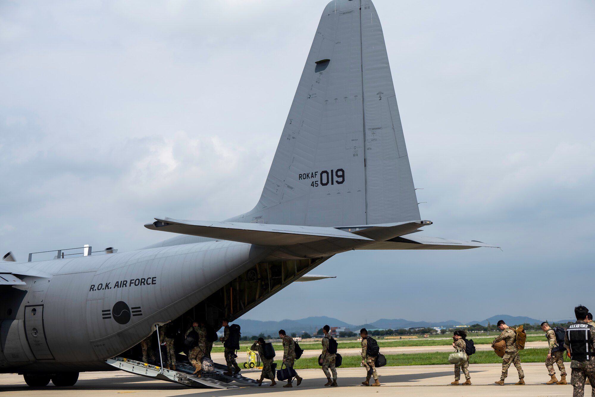 People walk on the flightline with planes parked.