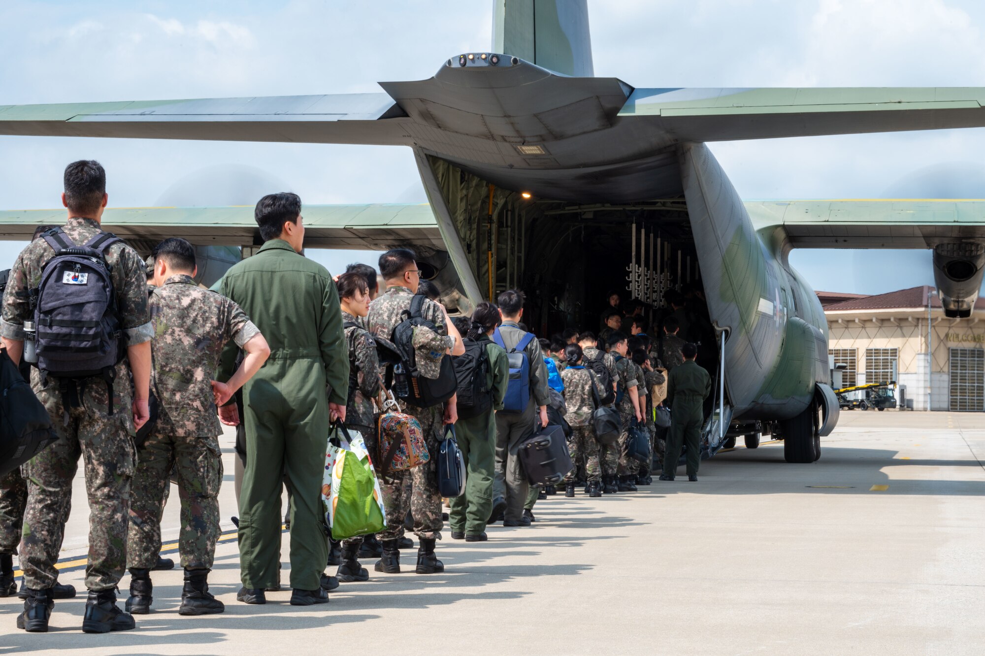 People walk on the flightline with planes parked.