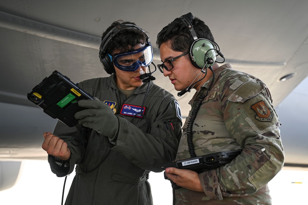 U.S. Air Force Senior Airman Daniel Fragoso III, left, 351st Air Refueling Squadron boom operator and Airman 1st Class Luis Santos Jr., 52nd Logistics Readiness Squadron fuels distribution specialist, coordinate refueling operations for a KC-135 Stratotanker aerial refueling aircraft assigned to the 100th Air Refueling Wing, during hot refueling training.