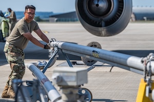 U.S. Air Force Tech Sgt. Kristoffer Sendayen, 52nd Logistics Readiness noncommissioned officer in charge of fuels facilities, pushes a mobile pantograph into position next to a KC-135 Stratotanker aerial refueling aircraft assigned to the 100th Air Refueling Wing, during hot refueling training.