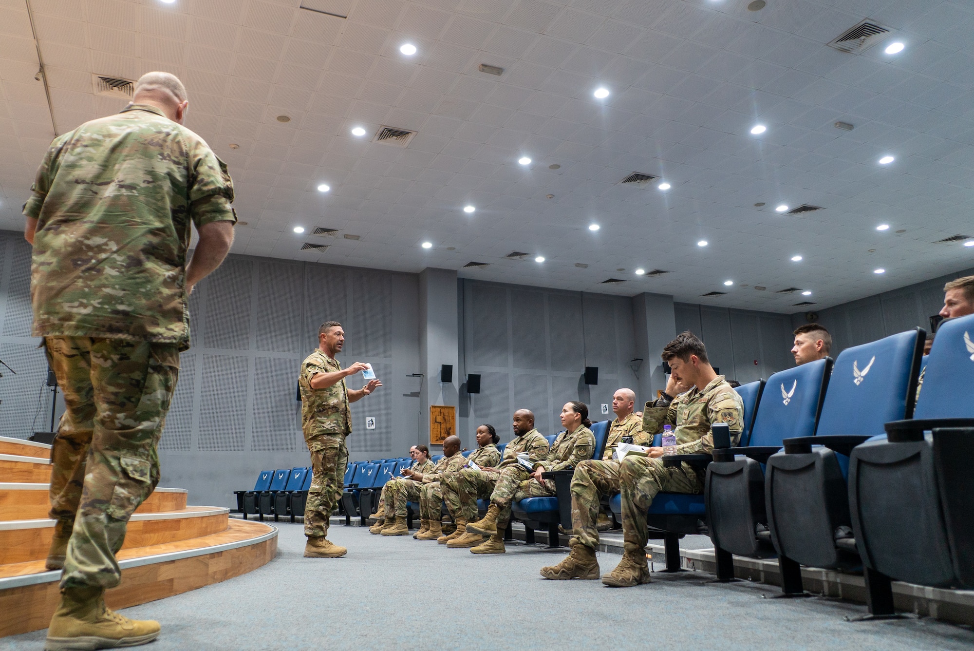 AFCENT ARC advisors on the left of frame speak to a crowd right of frame