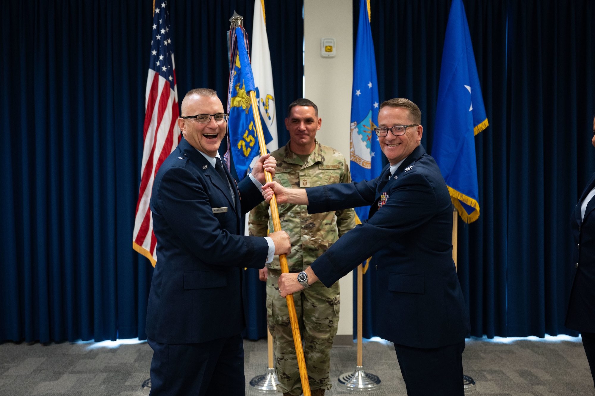 Two Airmen pass a guidon.