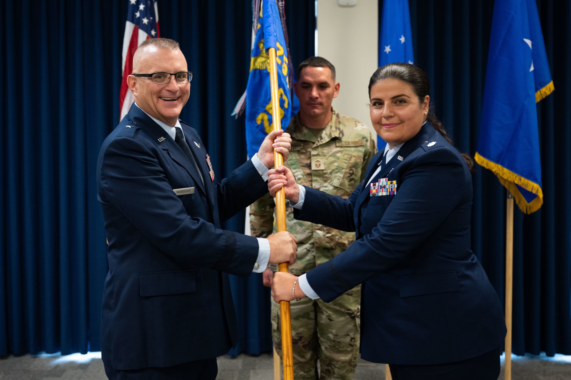 Two Airmen pass a guidon.