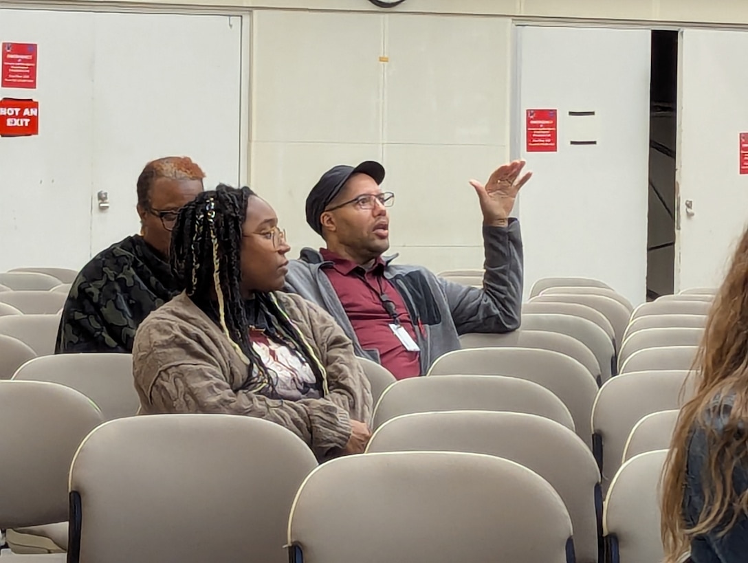 men and women sit in auditorium seats