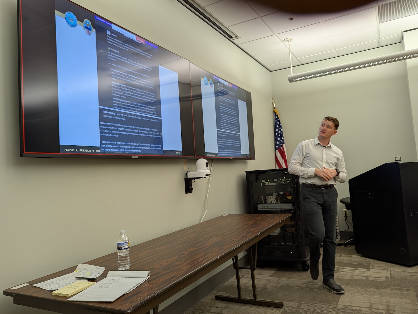 man in business attire stands in front of presentation slides
