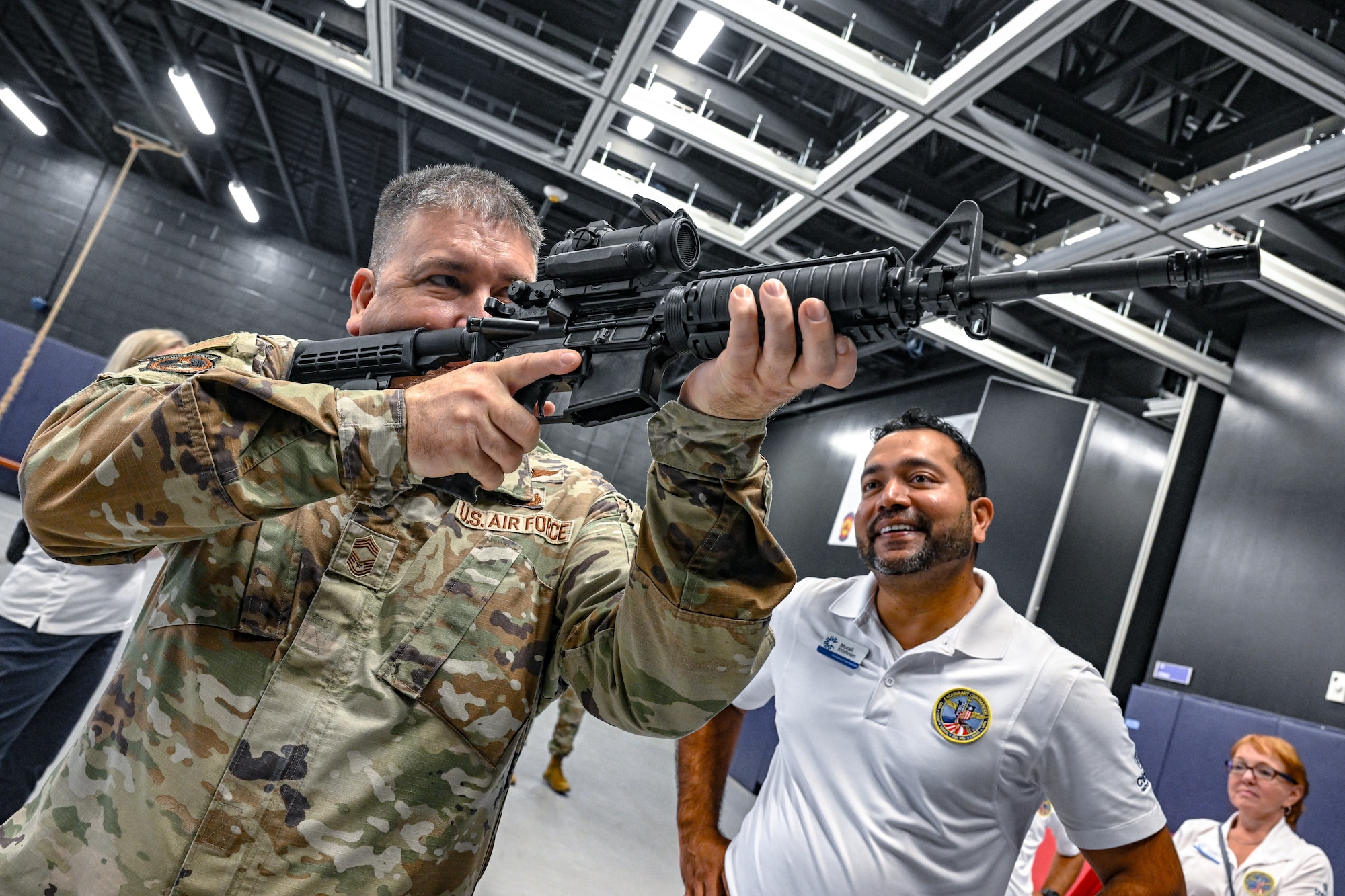 Chief Master Sgt. Gary Gardner, training manager with the 80th Aerial Port Squadron, shows a civic leader from Dobbins Air Reserve Base, Georgia, how to hold an M4 carbine rifle on Aug. 14, 2025, at Youngstown Air Reserve Station, Ohio.
