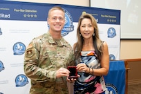 Commander in uniform holds coin box with president of the Chamber.