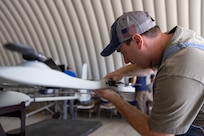 Gavin Abel, Lockheed Martin, assembles a Stalker unmanned aircraft system (UAS) during a technical demonstration held at Outlying Landing Field Seagle in Twentynine Palms, Calif. May 19-21, 2025. The U.S. Naval Research Laboratory in conjunction with the Operational Energy Capability Improvement Fund with the Office of the Assistant Secretary of Defense for Energy, Installations, and Environment, and the Marine Corps Expeditionary Energy Office (E2O) conducted the demonstration aiming to develop a technology for Navy vessels to "see over the horizon" using a combination of stratospheric high-altitude balloons (HABs) and unmanned aircraft.  (U.S. Marine Corps photo by Pfc. Jozef Mejewski/Released)