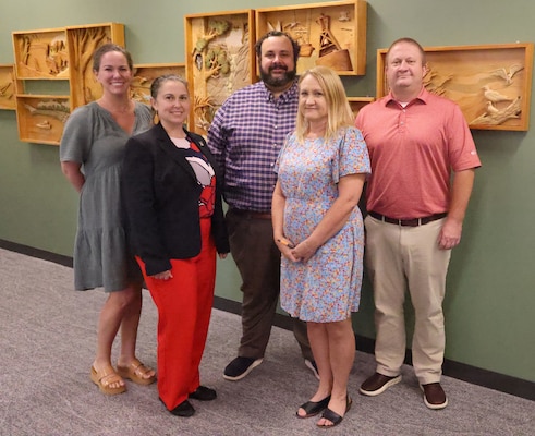 Five people standing in front of a wall.