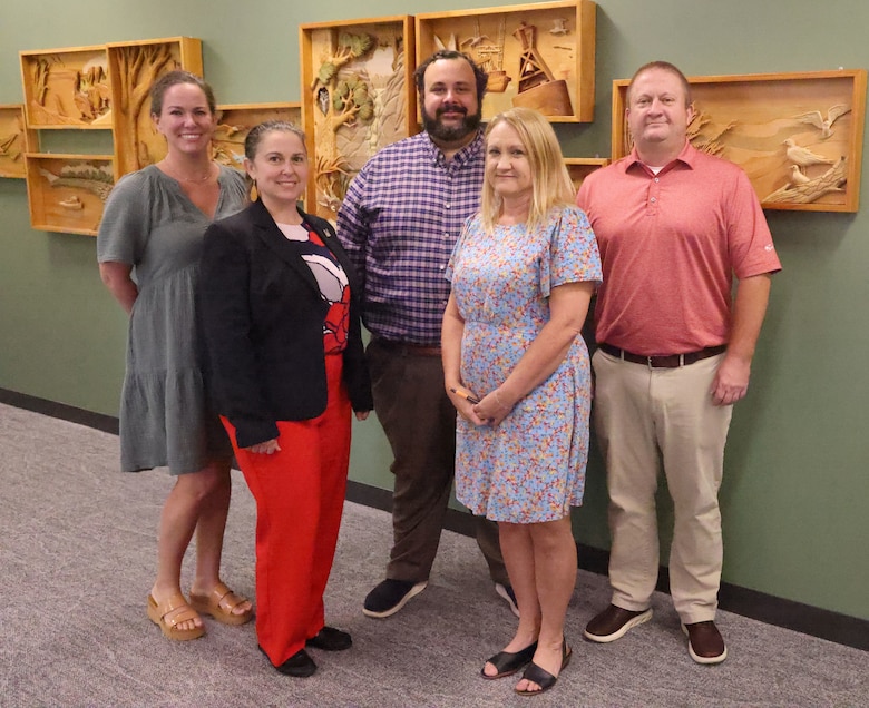 Five people standing in front of a wall.
