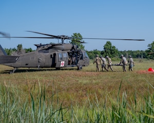 Airmen and soldiers carry stretcher to helicopter