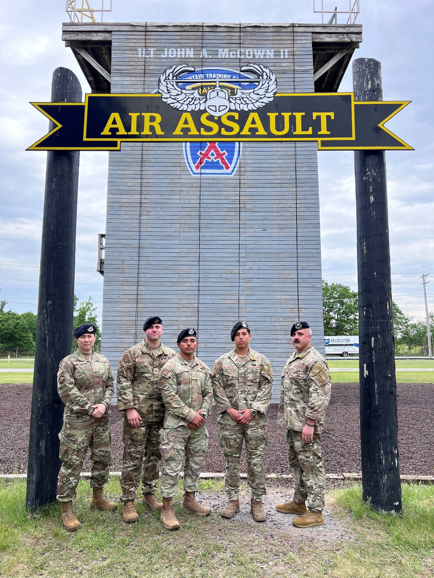 Five uniformed personnel stand below an archway posing for a picture.