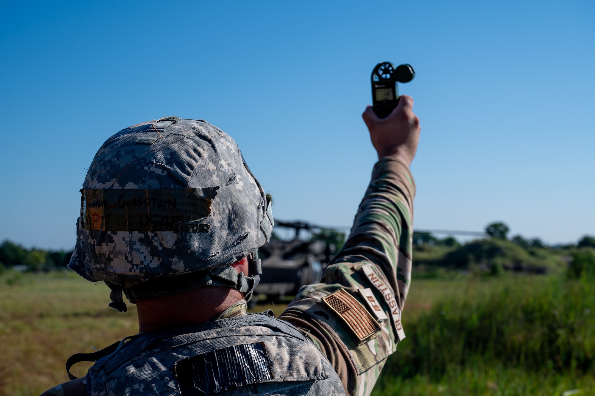 Airman in camo holds handheld anemometer
