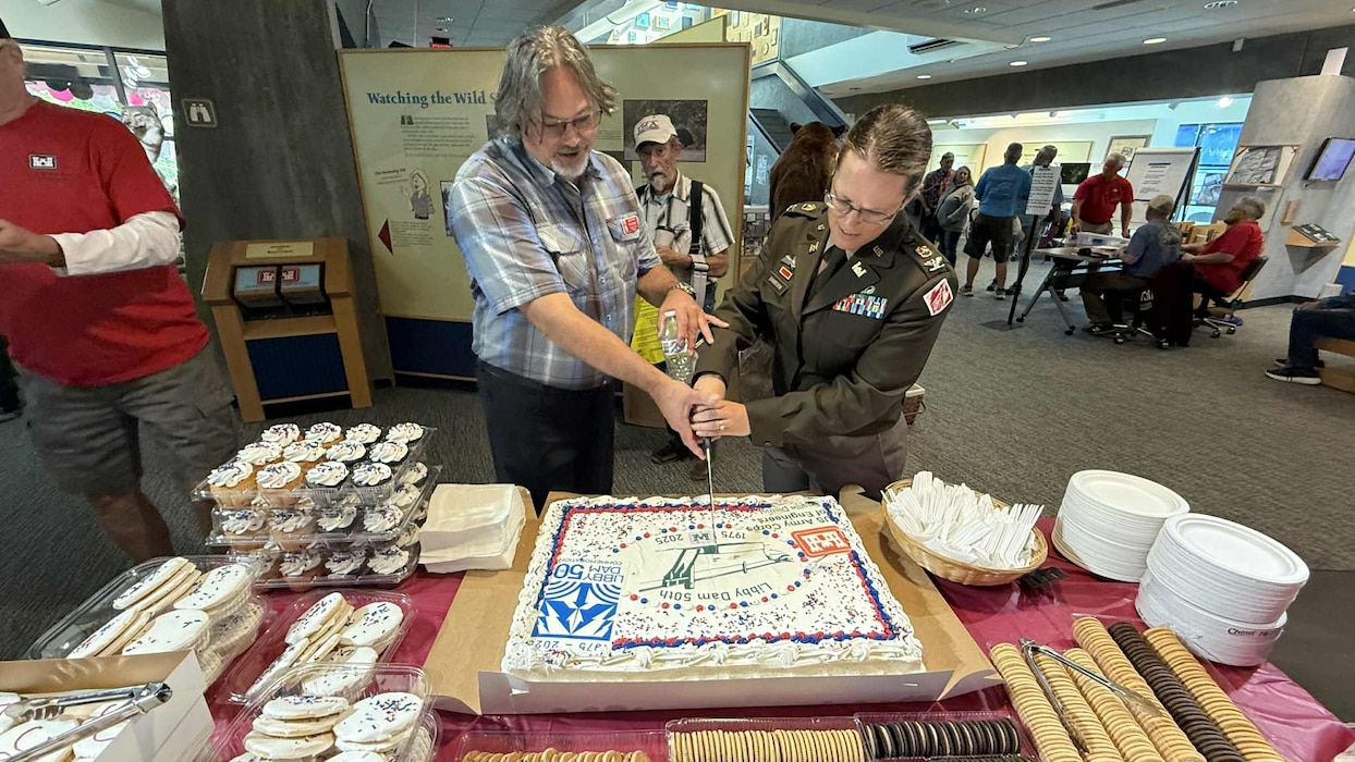Libby Dam Operating Project Manager Rick Spiger and U.S. Army Corps of Engineers, Seattle District Commander Col. Kathryn Sanborn cut a slice of cake, to celebrate Libby Dam's 50th commemoration, Aug. 23, 2025. The event, which included a formal ceremony with Presentation of Colors and a memorial unveiling, included walking across the top of the dam and the Treaty Tower.