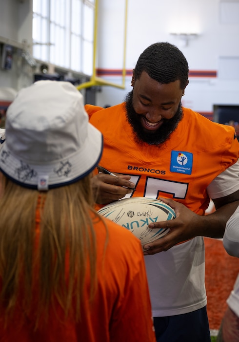 U.S. Air Force Airman First Class Christina P. Gein, 50th Force Support Squadron, Schriever Space Force Base, receives an autograph from a Denver Broncos player during the USAA Salute to Service Boot Camp, at Broncos Park, Englewood, Colorado, August 21, 2025. During the boot camp, service members from multiple installations were invited to observe a Broncos practice and meet the players. (U.S. Space Force photo by Ethan Johnson)