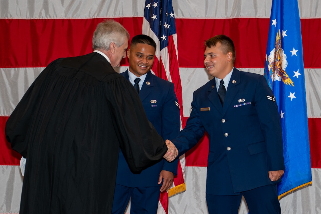 Honorable Judge Mark Hornsby, shakes the hands of U.S. Air Force Airman 1st Class Atson Nameta, 2nd Logistics Readiness Squadron individual protection equipment apprentice, and Airman 1st Class Tykhon Rudenok, 2nd Civil Engineer Squadron heating, ventilation and air conditioning apprentice, after administering the Oath of Allegiance during a Naturalization Ceremony at Barksdale Air Force Base, Louisiana, July 15, 2025. Hornsby, who administered the Oath of Allegiance, is the U.S. Magistrate for the Western District of Louisiana. (U.S. Air Force photo by Airman 1st Class Jaiyah Lewis)